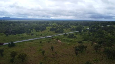 Aerial view of a road cutting through a green landscape under a cloudy sky with Stock Footage 313316438