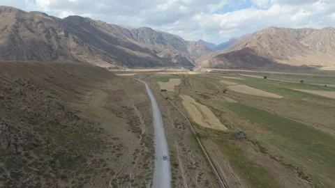Aerial view of a road through a patchwork farmland valley, Kyrgyzstan Stock Footage 347241796