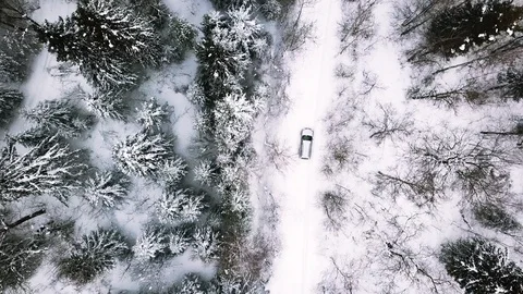 Aerial view of the road through a winter forest with a moving car. Footage Stockbeeldmateriaal 130113407