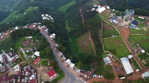 Aerial view of a road winding through a rural area with buildings and greenery Stock Footage 317837680