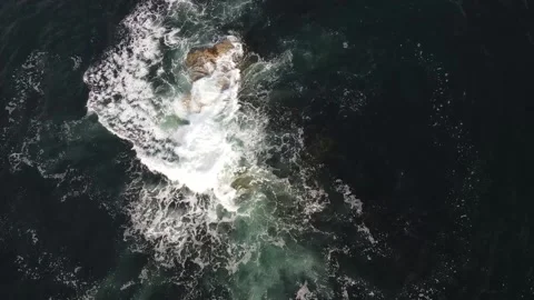 Aerial view of a rock formation with ocean waves hitting and splashing sea Stock Footage 166201582