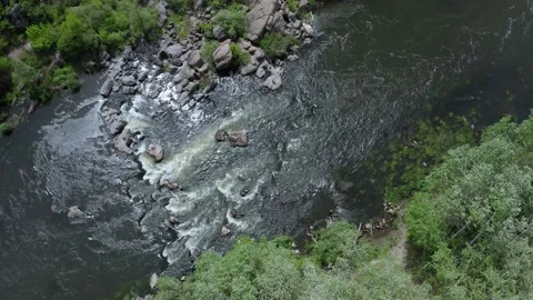 Aerial view of rocks across a section of a flowing stream. Trees and large stone Stock Footage 149212655