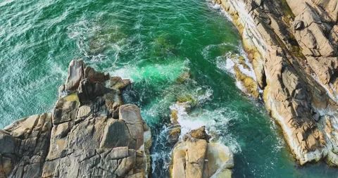 Aerial view of rocks under the abyss with sea water and blue waves Stock Footage 297745347