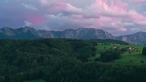 Aerial view of rocky alpine mountain peaks under vibrant pink dusk clouds Stock Footage 345614688