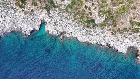 Aerial view of rocky coastline cliffs with sea waves crashing against shore Stock Footage 345151244