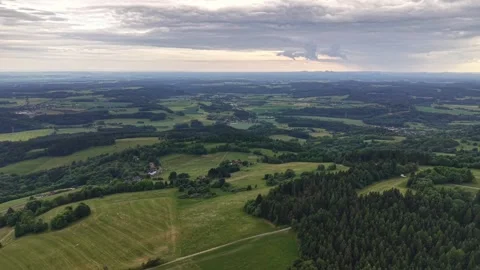 Aerial view of rolling countryside fields and forests under expansive valley Stock Footage 348176868
