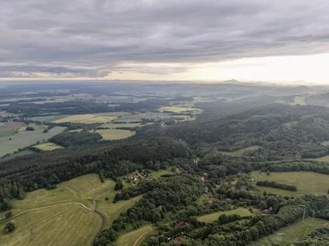Aerial view of rolling countryside with fields and forest under a cloudy sky Stock Photos