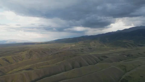 Aerial view of rolling dark hills beneath a stormy, overcast sky. Stock Footage 341270312