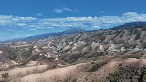 Aerial View of Rolling Desert Hills and Majestic Mountains Xinjiang China Stock Footage 346585917