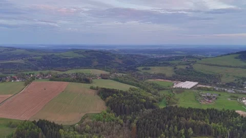 Aerial view of rolling farmland patchwork fields, forested hills, and small Stock Footage 347913320