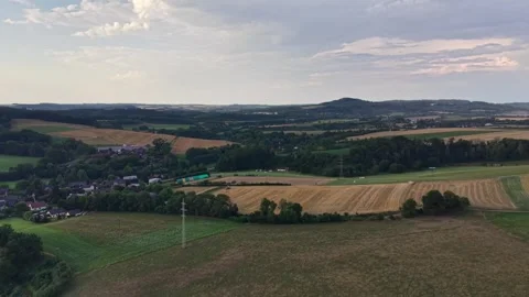Aerial view of rolling farmland, patchwork fields, small village along horizon, Stock Footage 348504254