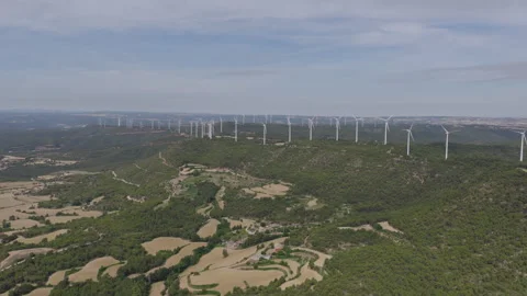 Aerial view of rolling green hills and fields with a large wind farm on the Stock Footage 337975462
