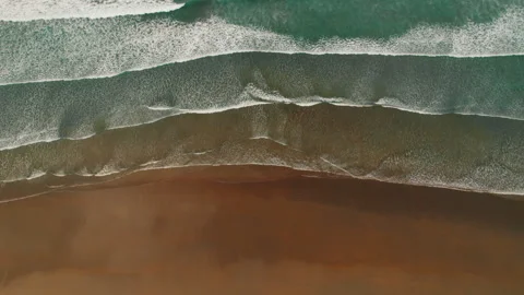 Aerial view of rolling waves over brown sand on a quiet tropical beach Stock Footage 342460346