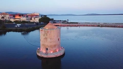 Aerial View A romantic ancient windmill on a sea lagoon at sunset Stock Footage 107847819