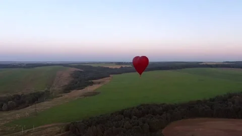 Aerial view romantic balloon flight in the form of a large red heart at sunset. Stock Footage 137975405