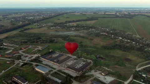 Aerial view romantic balloon flight in the form of a large red heart at sunset. Stock Footage 137975413