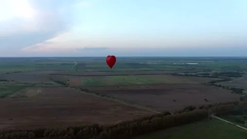 Aerial view romantic balloon flight in the form of a large red heart at sunset. Video stock 137975474