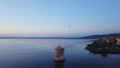 Aerial view of a romantic windmill on a calm sea lagoon at dusk, with seagulls Stock Footage 107848033
