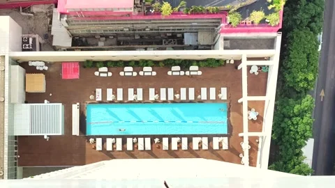 Aerial view of the rooftop pool with people and sun loungers around it. Relaxing Stock Footage 165489253
