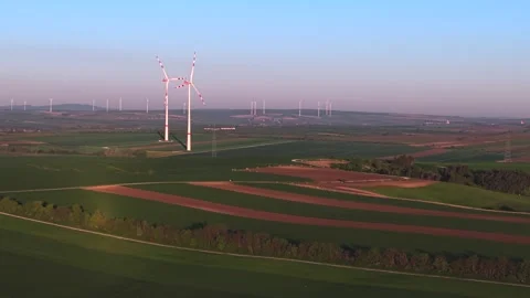 Aerial view of rotating wind turbines in a vast green landscape with fields.. Stock Footage 337471363