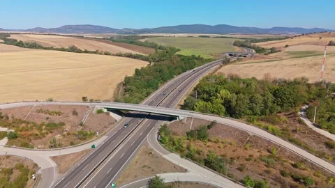 Aerial view of route 21 interchange in Pásztó amid green farmland hills Stock Footage 345995431