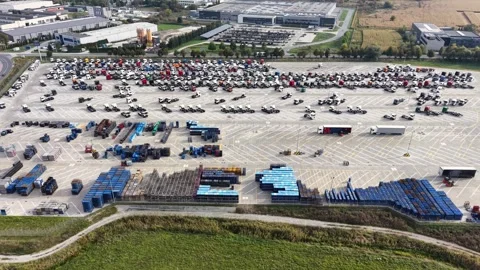 Aerial view of rows of parked new trucks and trailers in a large paved parking Видео 347414730