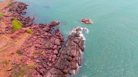 Aerial view rugged beach edged by crimson stones Stock Footage 305366720