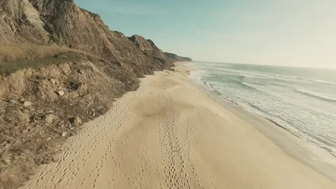 Aerial view of rugged cliffs beside a sandy beach Stock Footage 341826323