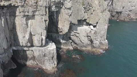 Aerial view of rugged limestone cliffs and sea caves on the coast of Swanage, UK Stock Footage 342764980
