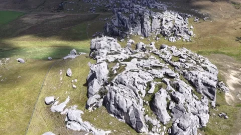 Aerial view of rugged limestone outcrops and rolling alpine grasslands on New Stock Footage 337139185