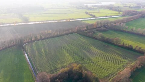 Aerial view of rural fields with crop rows tree shadows canal and farm buildings Stock Footage 323025594