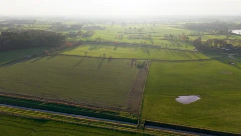Aerial view of rural fields with tree lined roads water patches and scattered Stock Footage 323011813