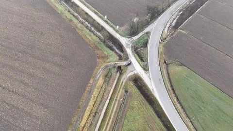 Aerial view of a rural intersection with fields and a curved road on a clou.. Stock Photos