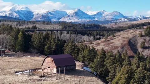 Aerial view of rustic barn and snow-capped mountains in rural valley Stock Footage 332040403