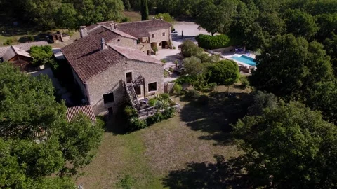 Aerial view of a rustic stone estate with a pool surrounded by lush Stock Footage 282501539