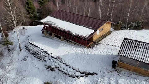 Aerial View of Rustic Wooden Cabin in Snowy Mountain Landscape Stock Footage 335543331