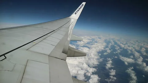 Aerial View from Ryanair Plane Window Over Fluffy Clouds and Deep Blue Sky Stock Footage 335921010