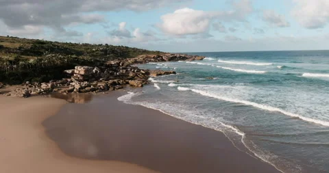 Aerial view of the sandy beach and rugged, rocky coastline Stock Footage 153759434