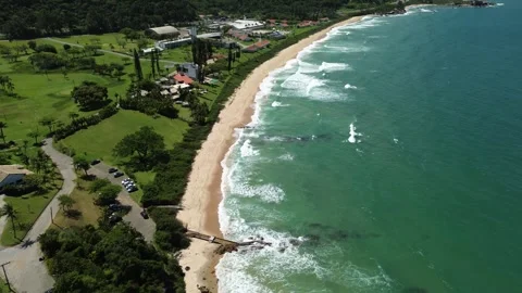 Aerial view of a sandy beach with green hills and ocean waves in Itapema, Brazil Stock Footage 329078136