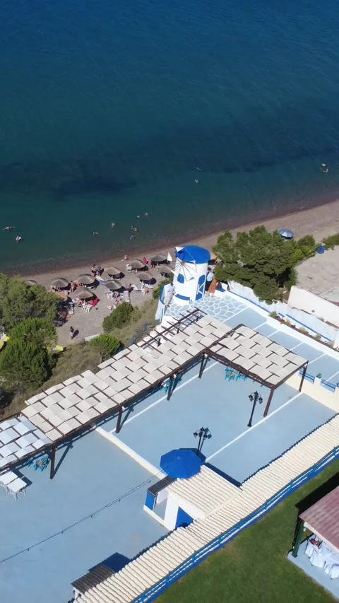 Aerial view of a sandy beach with a hilltop windmill on Greek island Stock Footage 344093654