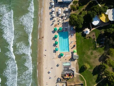 Aerial view of sandy beach, ocean waves, swimming pool, and resort area Stock Photos