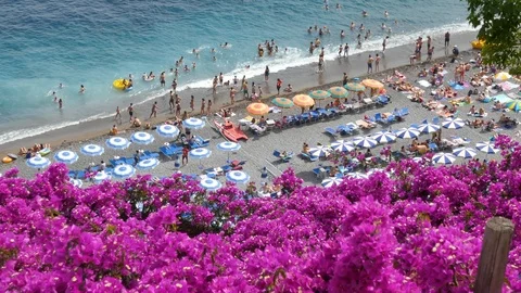 Aerial view of sandy beach with rows of umbrellas, swimming people in sea flower Stock Footage 112816130