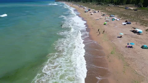 Aerial view of a sandy beach with scattered tents and umbrellas along the Stock-Footage 281785938