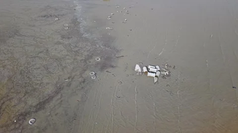Aerial view of sandy beach with scattered trash and waterline detail Stock Footage 344048798