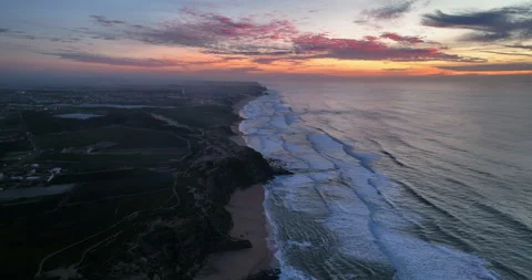 Aerial view of a sandy beach with waves rolling in during the sunset. Drone Stock Footage 221447387