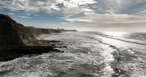 Aerial view of a sandy beach with waves rolling in during the sunset. Drone Stock Footage 221721490