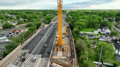 Aerial View Scaling a Massive Crane Parked on a Highway Overpass Stock Footage 240694886