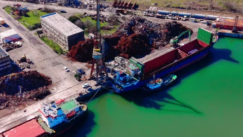 Aerial view of scrap metal loading onto cargo ship at port Stock Footage 331941942