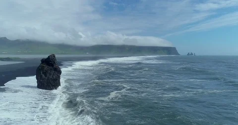 Aerial view of sea stack and crashing waves off Icelandic coast Видео 79834854