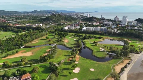 Aerial view of seaside golf course at sunrise with green fairways and water 库存影片 316750056